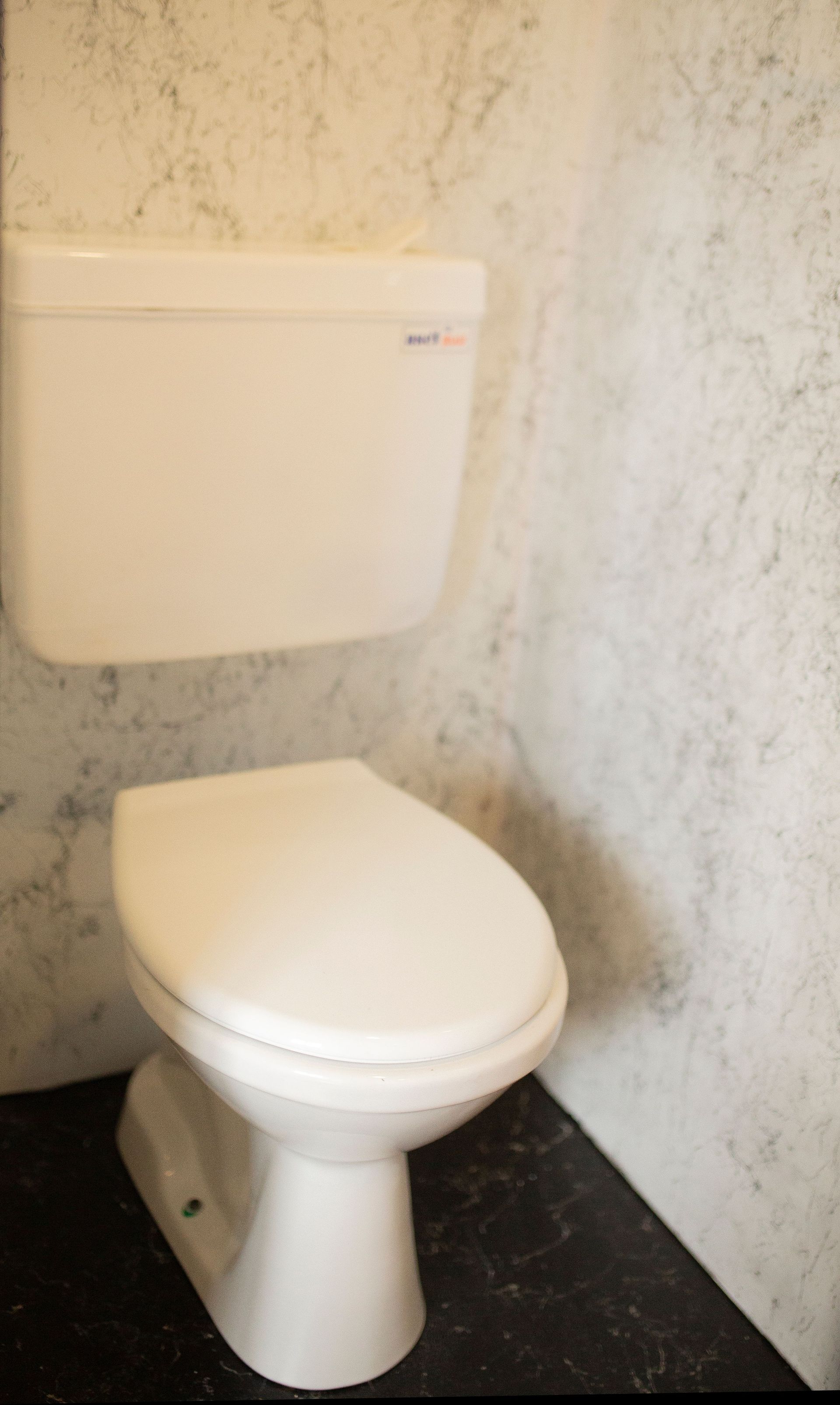 A minimalist white toilet against a marble wall in a sleek bathroom setting.